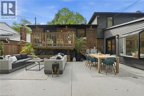 Spacious concrete patio with dual outdoor living areas, including a dining space with a large table and an additional seating area - 345 Rankin Drive, Burlington, ON - Outdoor With Deck Patio Veranda With Exterior