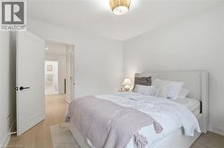 Bedroom with light wood-finish flooring and white walls - 