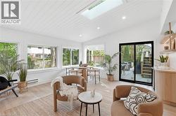 Open concept living area featuring a vaulted wood-paneled ceiling, skylight, recessed lighting, and light wood-finish flooring - 