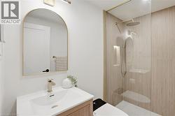 Bathroom featuring a glass-enclosed shower with fluted wall tiling, a rainfall showerhead, and a recessed niche - 
