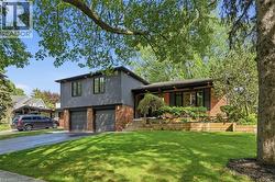 Split-level residence featuring a two-car garage, dark gray siding, and brick accents - 