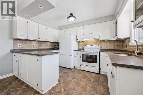 Bright kitchen featuring white cabinetry, dark countertops, a tiled backsplash, and recessed lighting - 47 Oakhurst Crescent, Kitchener, ON - Indoor Photo Showing Kitchen