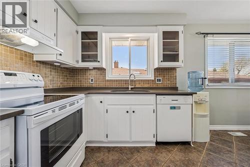 Kitchen featuring white cabinetry, dark countertops, and a tiled backsplash - 47 Oakhurst Crescent, Kitchener, ON - Indoor Photo Showing Kitchen With Double Sink