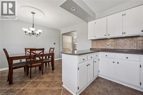 Open kitchen and dining area featuring white cabinetry, dark countertops, tiled backsplash, and ceramic tile flooring - 47 Oakhurst Crescent, Kitchener, ON - Indoor