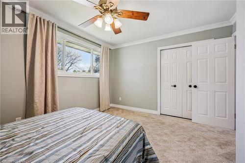 Carpeted room featuring a ceiling fan with wood-finish blades, a multi-pane window, white trim molding, and bi-fold closet doors - 47 Oakhurst Crescent, Kitchener, ON - Indoor Photo Showing Bedroom