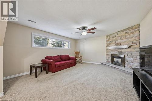 Spacious room featuring a stacked stone fireplace with a hearth and mantel, large horizontal windows, and a ceiling fan with integrated lighting - 47 Oakhurst Crescent, Kitchener, ON - Indoor Photo Showing Living Room With Fireplace