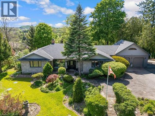 Stone façade residence with a multi-car garage, mature landscaping, and a sloped roofline - 91 Limerick Drive, Kitchener, ON - Outdoor With Facade