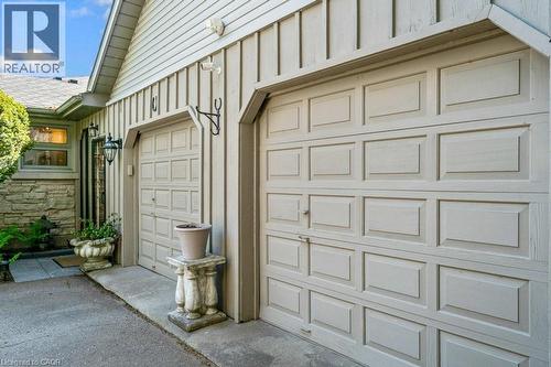 Two paneled garage doors, board and batten siding, stone facade, and exterior wall lanterns - 91 Limerick Drive, Kitchener, ON - Outdoor With Exterior