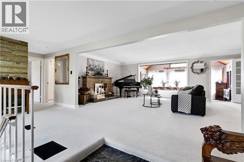 Spacious living area featuring light-colored carpeting, a brick fireplace with a detailed screen, and an expansive window line - 91 Limerick Drive, Kitchener, ON - Indoor