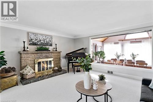Living area featuring a stone-clad fireplace with a brass firebox, crown molding, and light-toned wall paint - 91 Limerick Drive, Kitchener, ON - Indoor Photo Showing Living Room With Fireplace