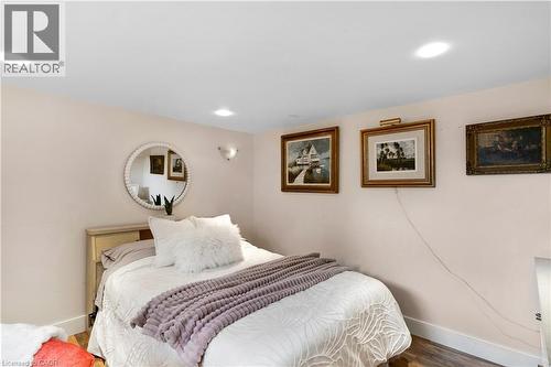 Recessed lighting and a wall-mounted sconce illuminate this room featuring light-colored walls, wood-finish flooring, and white baseboards - 91 Limerick Drive, Kitchener, ON - Indoor Photo Showing Bedroom