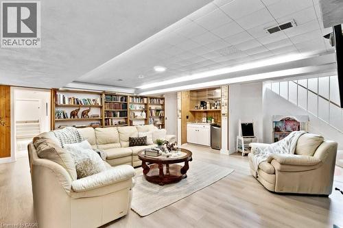 Spacious recreation room featuring recessed lighting, extensive built-in shelving, wood-finish flooring, and a wet bar with integrated cabinetry and a beverage cooler - 91 Limerick Drive, Kitchener, ON - Indoor Photo Showing Living Room