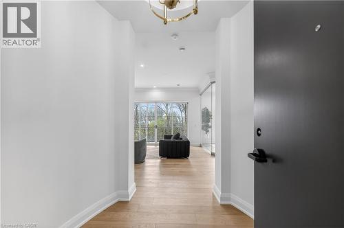 Entryway featuring a dark gray door with matte black hardware, leading to a space with wood-finish flooring, white walls, and a recessed lighting - 2 Arbourvale Common Unit# 410, St. Catharines, ON - Indoor Photo Showing Other Room