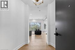 Entryway featuring a dark gray door with matte black hardware, leading to a space with wood-finish flooring, white walls, and a recessed lighting - 