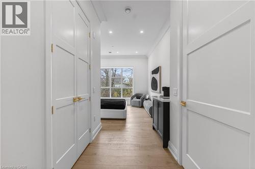 Hallway featuring light wood-finish flooring, recessed lighting, and white paneled doors with brass hardware - 2 Arbourvale Common Unit# 410, St. Catharines, ON - Indoor Photo Showing Other Room