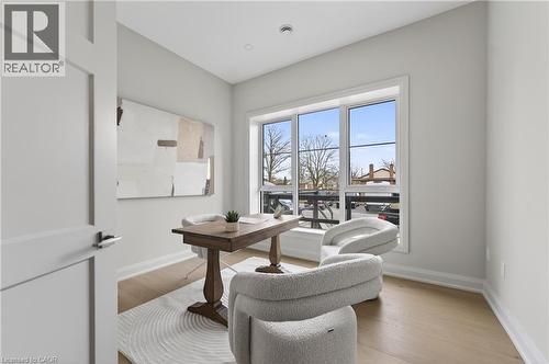Well-lit room featuring a large window, light wood-finish flooring, recessed lighting, and a modern interior door - 2 Arbourvale Common Unit# 410, St. Catharines, ON - Indoor