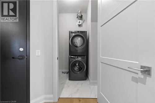 Dedicated laundry area featuring stacked front-load washer and dryer units - 2 Arbourvale Common Unit# 410, St. Catharines, ON - Indoor Photo Showing Laundry Room