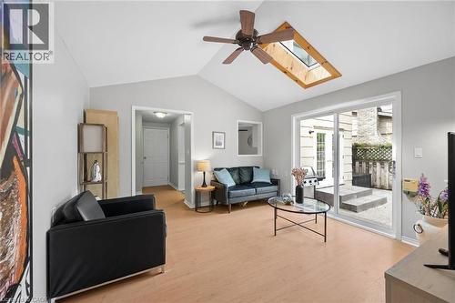 Vaulted ceiling living area featuring a skylight, ceiling fan, wood-finish flooring, and sliding glass doors opening to a stone patio - 50 Lewis Crescent, Kitchener, ON - Indoor Photo Showing Living Room