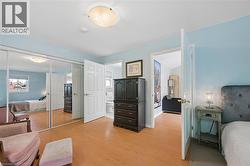 Bedroom featuring wood-finish flooring, mirrored closet doors, and an overhead flush-mount light fixture - 