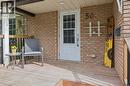 Brick exterior with a covered porch featuring a white entry door with glass inserts, a wood-finish deck, and black metal railings - 50 Lewis Crescent, Kitchener, ON  - Outdoor With Deck Patio Veranda With Exterior 