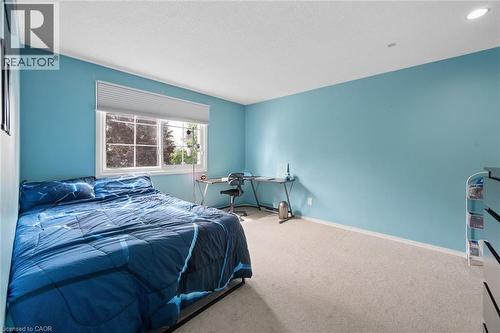 Brightly lit room featuring a large window with white blinds, light-colored carpeting, blue walls, a white ceiling, and recessed lighting - 50 Lewis Crescent, Kitchener, ON - Indoor Photo Showing Bedroom