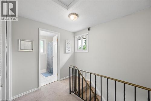 Upper landing featuring light-toned carpeting, a window with white trim, and a metal staircase railing - 50 Lewis Crescent, Kitchener, ON - Indoor Photo Showing Other Room