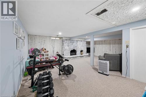 Spacious room featuring a stone-faced fireplace with hearth, light-colored carpeting, recessed lighting, and painted paneling - 50 Lewis Crescent, Kitchener, ON - Indoor