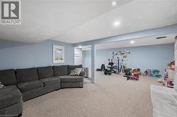 Spacious lower-level area featuring light-toned carpeting and soft blue walls - 