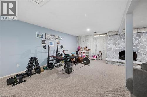 Spacious finished basement featuring recessed lighting, light blue wall paint, a stone-clad fireplace, and neutral carpet flooring - 50 Lewis Crescent, Kitchener, ON - Indoor Photo Showing Gym Room
