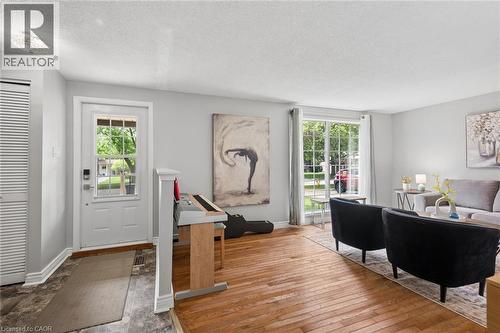 Hardwood flooring extends throughout this interior space, featuring a white paneled door with glass inserts and a large window with white framing - 50 Lewis Crescent, Kitchener, ON - Indoor