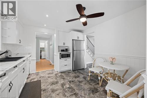 Bright kitchen featuring white cabinetry, a black sink, stainless steel appliances, and a modern ceiling fan with light - 50 Lewis Crescent, Kitchener, ON - Indoor Photo Showing Kitchen With Upgraded Kitchen