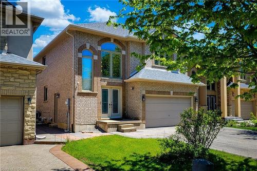 Brick facade residence featuring arched window details, double front entry doors, an attached garage, a paved driveway, and a manicured lawn - 197 Cloverleaf Drive, Ancaster, ON - Outdoor