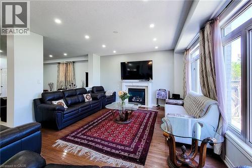 Spacious living area featuring wood-finish flooring, recessed ceiling lighting, and a white mantel fireplace - 197 Cloverleaf Drive, Ancaster, ON - Indoor Photo Showing Living Room With Fireplace