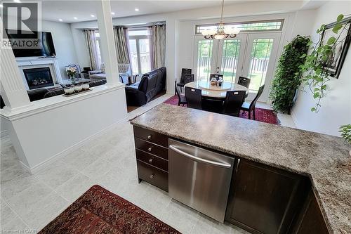 Kitchen island with a dark wood-finish base, speckled countertop, and integrated stainless steel dishwasher - 197 Cloverleaf Drive, Ancaster, ON - Indoor With Fireplace