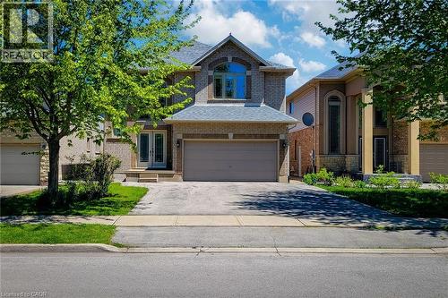 Brick exterior with a stone accent facade, featuring a prominent arched window and a double garage - 197 Cloverleaf Drive, Ancaster, ON - Outdoor With Facade