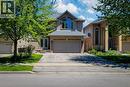 Brick exterior with a stone accent facade, featuring a prominent arched window and a double garage - 197 Cloverleaf Drive, Ancaster, ON  - Outdoor With Facade 