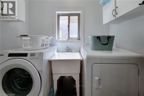 Dedicated laundry area featuring a utility sink, upper cabinetry with brushed nickel pulls, and a window providing natural light - 197 Cloverleaf Drive, Ancaster, ON - Indoor Photo Showing Laundry Room