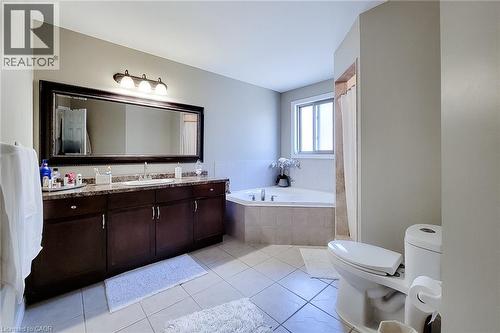 Spacious bathroom featuring a large vanity with double sinks, dark wood-finish cabinetry, and a stone-finish countertop - 197 Cloverleaf Drive, Ancaster, ON - Indoor Photo Showing Bathroom