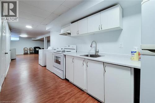 Functional kitchen area featuring white cabinetry, a stainless steel sink with a high-arc faucet, and white appliances including a range and refrigerator - 197 Cloverleaf Drive, Ancaster, ON - Indoor Photo Showing Kitchen
