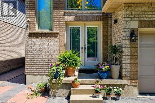 Brick exterior featuring a double-door entry with decorative glass inserts, a two-story window, a garage door with panel detailing, and a black exterior lantern - 197 Cloverleaf Drive, Ancaster, ON - Outdoor