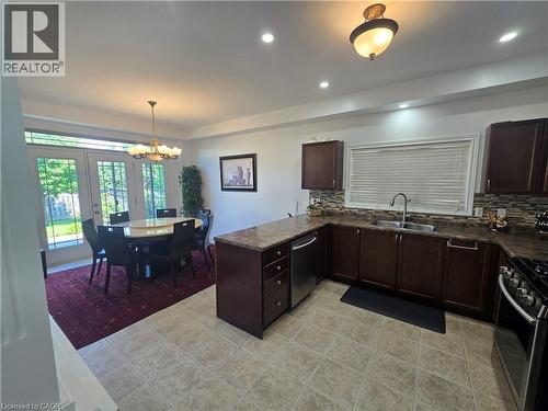 Open-concept kitchen and dining area featuring dark wood-finish cabinetry, stainless steel appliances, tile flooring, and French doors leading to exterior - 197 Cloverleaf Drive, Ancaster, ON - Indoor Photo Showing Kitchen With Upgraded Kitchen