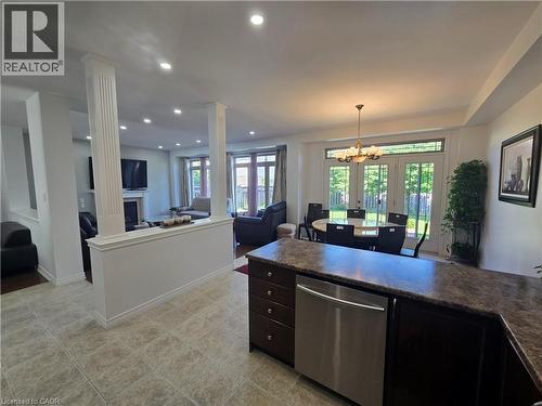 Kitchen area featuring a built-in stainless steel dishwasher, dark wood-finish cabinetry, and a speckled countertop - 197 Cloverleaf Drive, Ancaster, ON - Indoor With Fireplace