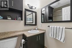 Bathroom vanity featuring dark wood-finish cabinetry, a white oval sink, and a light-colored countertop - 