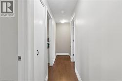 Hallway featuring wood-finish flooring, light grey painted walls, white trim, and flush-mount ceiling lighting - 
