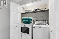 Dedicated laundry closet featuring a stackable washer and dryer, upper storage shelving, and bi-fold panel doors - 
