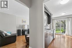 Kitchen area featuring wood-finish flooring, light grey cabinetry with brushed nickel hardware, and a stainless steel sink with a gooseneck faucet - 