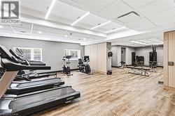 Fitness center featuring wood-finish flooring, ample natural light from multiple windows, and recessed lighting - 