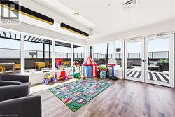 Spacious room featuring wood-finish flooring, full-height windows, dual glass panel doors, and linear pendant lighting - 