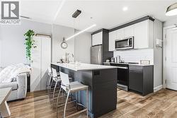 Modern kitchen featuring an expansive center island with seating, stainless steel appliances, two-tone cabinetry with crown molding, and a subway tile backsplash - 