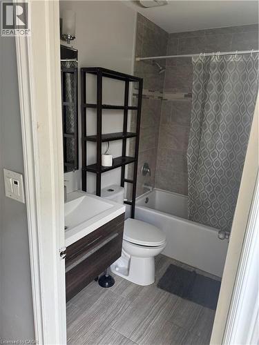 Bathroom featuring a contemporary floating vanity with integrated sink, a white bathtub with tile surround, and wood-finish flooring - 61 E Waterloo Drive Unit# 61, Kitchener, ON - Indoor Photo Showing Bathroom